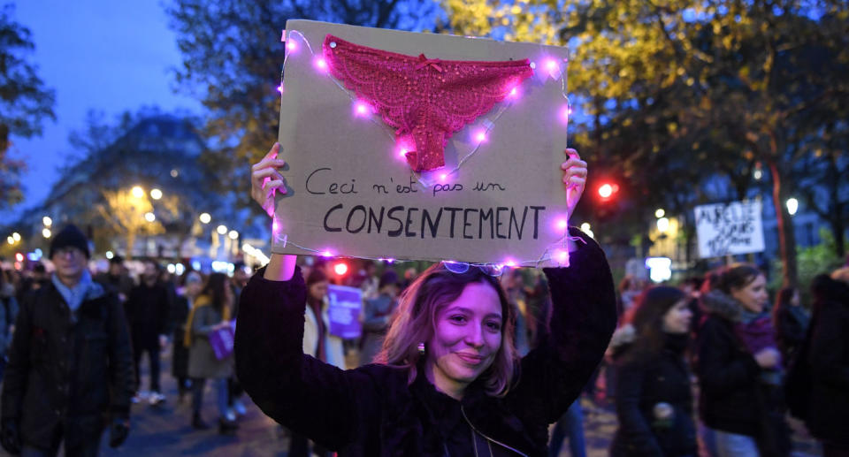 Women's underwear on placard held by woman taking part in Paris march against violence against women.