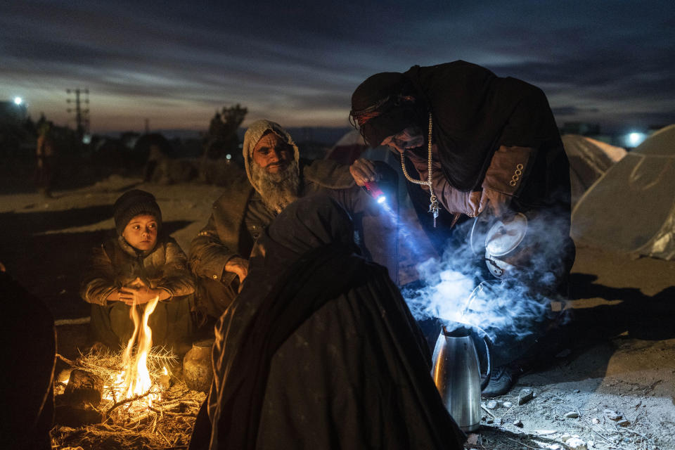 FILE - A family prepares tea outside the Directorate of Disaster office where they are camped, in Herat, Afghanistan, on Nov. 29, 2021. The United Nations is predicting that a record 274 million people – who together would amount to the world’s fourth most-populous country – will require emergency humanitarian aid next year in countries including Afghanistan, Ethiopia, Myanmar, Syria and Yemen as they face a raft of challenges such as war, insecurity, hunger, climate change and the coronavirus pandemic. (AP Photo/Petros Giannakouris, File)