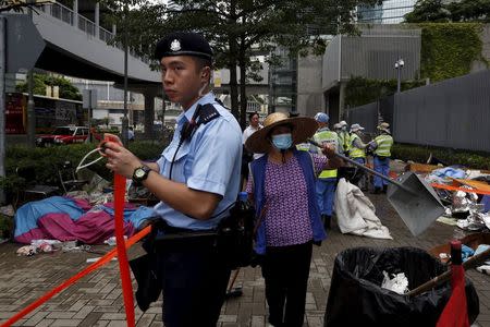 A policeman cordons off an area as a cleaner removes encampments outside the government headquarters in Hong Kong, China June 24, 2015. REUTERS/Bobby Yip