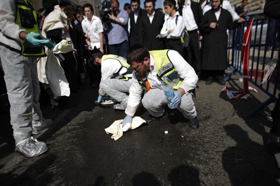 Members of the Israeli Zaka emergency response team clean blood at the scene of an attack at a Jerusalem synagogue