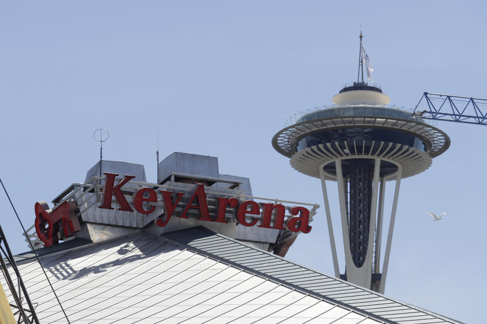 The top of the roof of KeyArena, which is currently undergoing a complete renovation, is shown with the Space Needle in the background, Thursday, June 25, 2020, in Seattle. Amazon has bought the naming rights to the arena, which will host a new NHL hockey team and the WNBA Basketball Seattle Storm, and will call the facility Climate Pledge Arena. (AP Photo/Ted S. Warren)