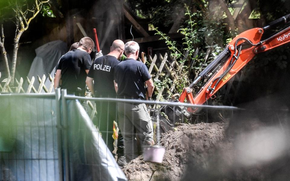 Police watch as a digger excavates the plot - AP