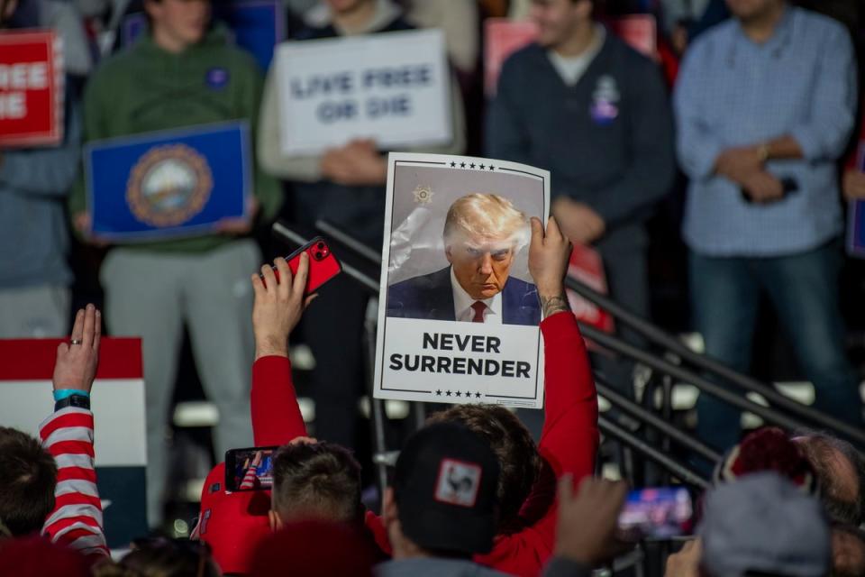 Donald Trump’s supporters in New Hampshire on 16 December hold a picture of his mugshot from criminal charges in Atlanta for an alleged scheme to overturn 2020 election results. (EPA)
