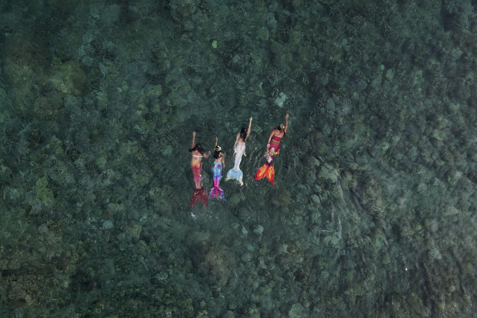 Queen Pangke Tabora (der) enseña a (de izq a der) Shelah Candado, Jennica Secuya y Meryll Louise Reque a nadar como sirenas en Mabini (Filipinas) el 22 de mayo del 2022. (AP Photo/Aaron Favila)