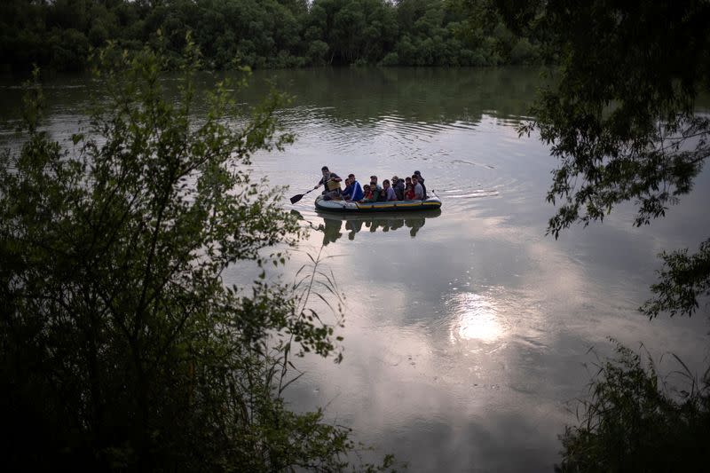 Un hombre en una balsa rema hacia la orilla después de cruzar a Estados Unidos desde México, en Los Ébanos