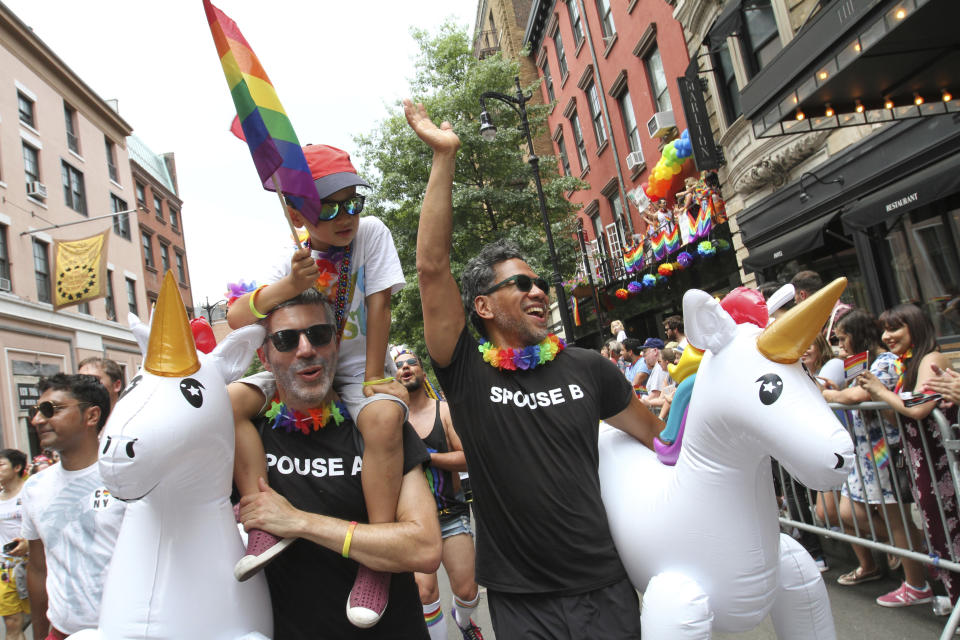 Adam Gwosdof, foreground left, and his spouse Brian Liem, foreground right, take part in the Gay Pride Parade with their son Milo Gwosdof-Liem, 5, atop Gwosdof’s shoulders, Sunday June 24, 2018 in New York. (AP Photo/Tina Fineberg)
