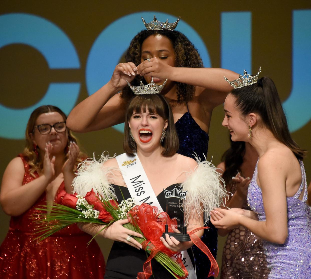 Reese Johnson, 17, of Monroe is crowned Miss Monroe County 2023 by Miss Monroe County 2022 Payton Perry-Radcliffe as Miss Monroe County Outstanding Teen 2022 MaKayla Dickinson hands her flowers Saturday, Aug. 19, 2023 at the 61st annual Miss Monroe County Scholarship Program at the Meyer Theater, La-Z-Boy Center at Monroe County Community College. Behind left is contestant Emilee Breitner, 22, of Ida.