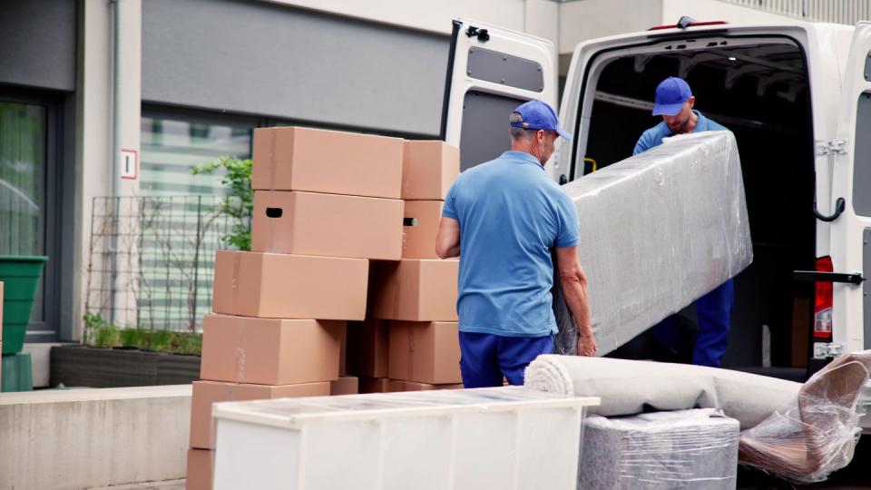 male workers in blue uniform unloading furniture