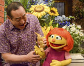 This image released by Sesame Workshop shows castmember Alan Muraoka, left, with Julia, an autistic muppet character debuting on the 47th Season of "Sesame Street." The popular children's TV show is celebrating its 50th season. (Zach Hyman/Sesame Workshop via AP)