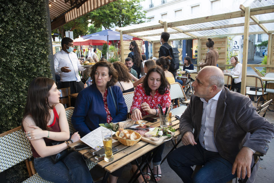 Anaïs Bulcao, 17, left, and her mother Nathalie Sartor, 57, second from right, enjoy nibbles and drinks at a Montmartre watering hole, "Le Saint Jean," with family friends on June 7, 2021 in Paris. Nathalie found readjusting to crowds tricky when France started to emerge from lockdown in mid-May. "We're no longer used to being with people," she said. (AP Photo/ João Luiz Bulcao)