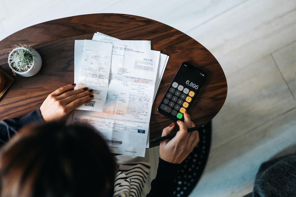 Someone using their phone's calculator with receipts in front of them