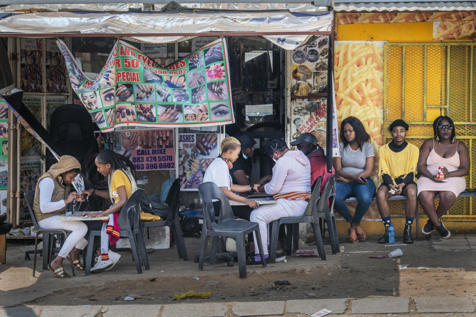 FILE - In this Sept. 16, 2020 file photo, customers have their nails done near the Baragwanath taxi rank in Soweto, South Africa. The country's success in bringing its first wave of COVID-19 under control has allowed it to almost fully reopen the economy, while monitoring for signs of a second surge, says the government's chief medical advisor. (AP Photo/Jerome Delay, File)