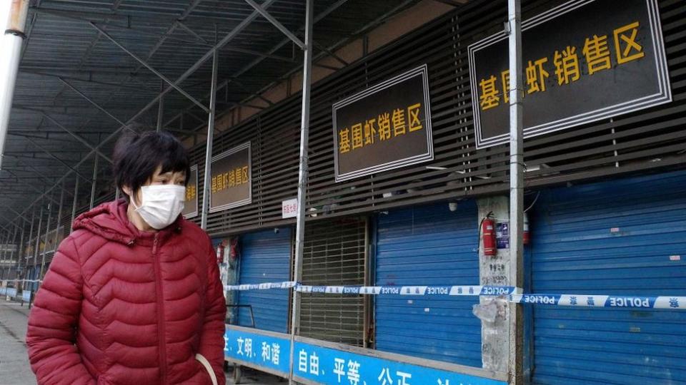 Una mujer camina por un mercado cerrado en Wuhan.