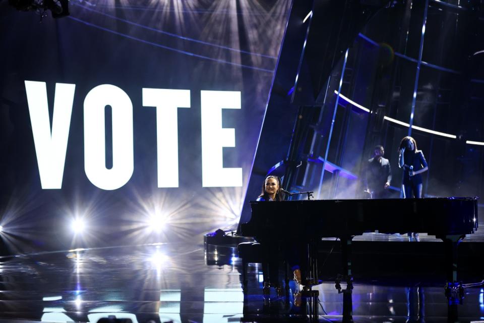 Demi Lovato, backed by a huge "Vote" sign, performs at the piano.