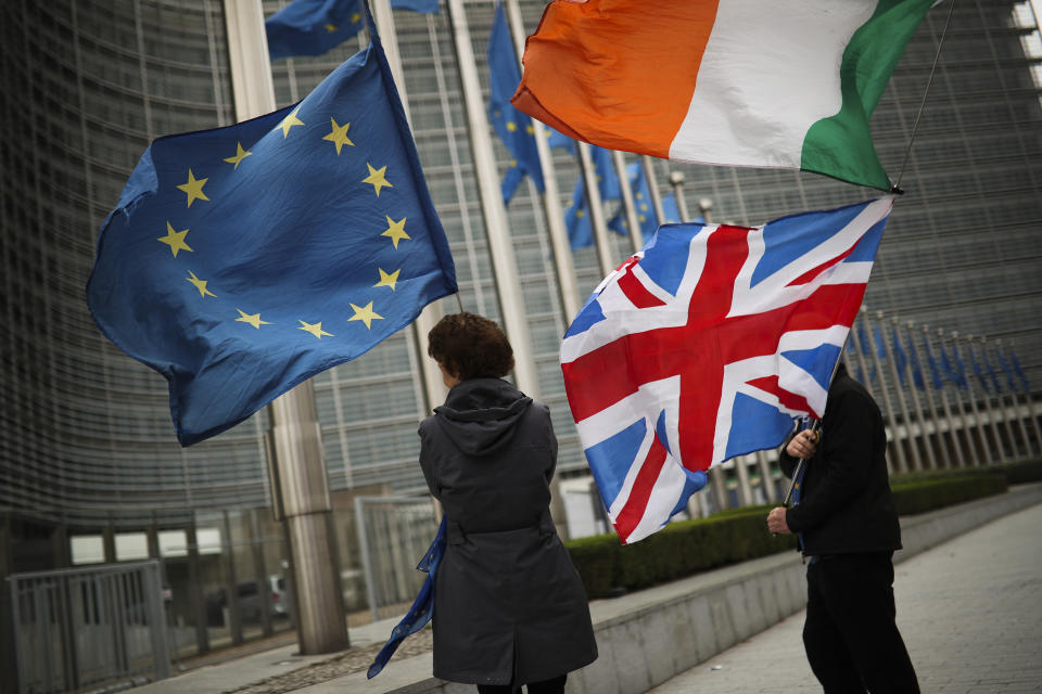 Two anti Brexit people hold EU, Ireland and Union Flags as they wait for the departure of UK Brexit secretary Stephen Barclay during his meeting with European Union chief Brexit negotiator Michel Barnier at the European Commission headquarters in Brussels, Friday, Oct. 11, 2019. The European Union said Friday that talks with the United Kingdom to find an amicable divorce with the United Kingdom are back on track, despite huge challenges and a tight end-of-month deadlime looming large. (AP Photo/Francisco Seco)