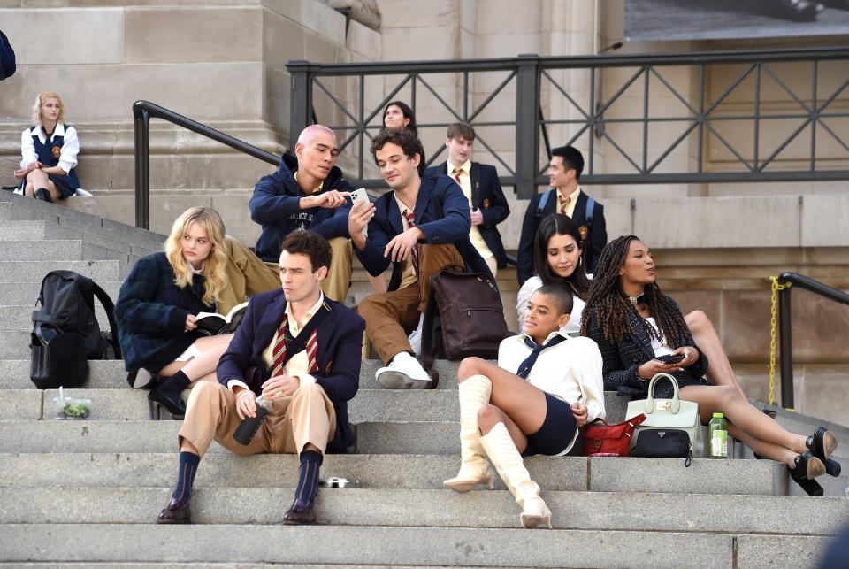 Aki, Julian, Luna, Monet, Max, Obie, and Audrey from the "Gossip Girl" reboot sitting on the MET stairs