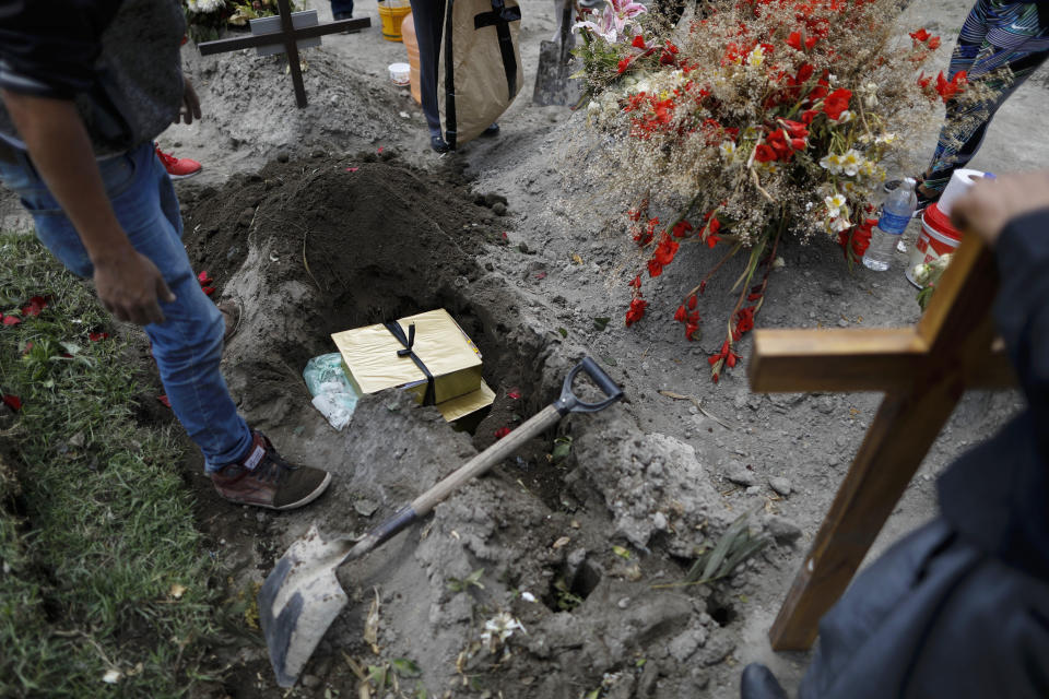 Boxes containing the flowers, lime and other symbolic elements used in the cross-raising ceremony are buried atop the grave of Luz Maria Gonzalez, as her family marks nine days since her burial, in the Municipal Cemetery of Valle de Chalco on the outskirts of Mexico City, Saturday, July 4, 2020. Maria Luz Gonzalez, 56, who had long suffered from asthma, diabetes and hypertension, died two days after her son, who was hospitalized for breathing problems and a cough before dying of complications said to be related to pneumonia and undiagnosed diabetes. (AP Photo/Rebecca Blackwell)