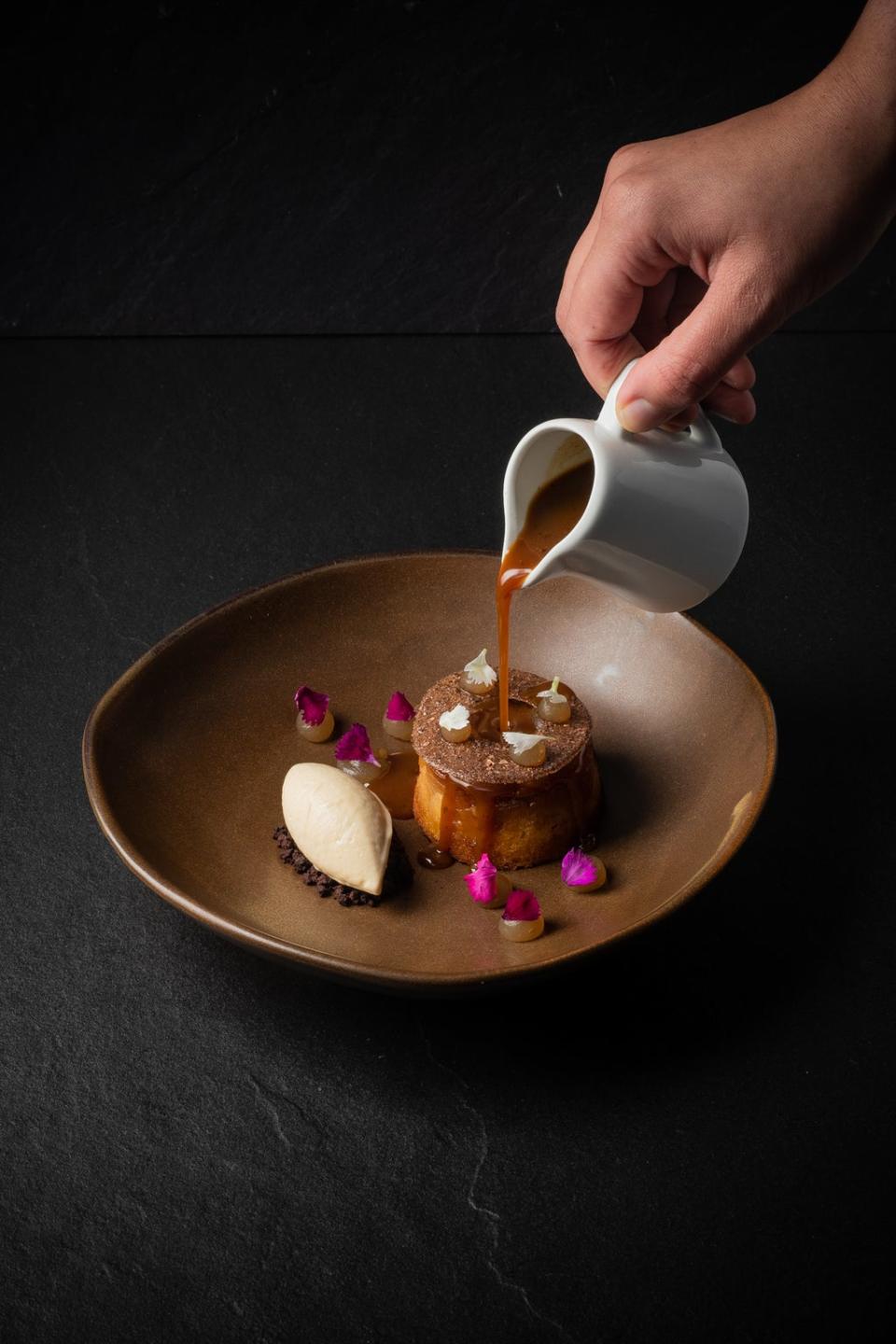 A Hiakai dessert of warm brown butter and pear cake, cocoa husk opaline, chocolate crumbs, roasted parsnip ice cream drizzled with horopito butterscotch (Hiakai)