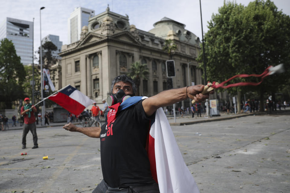 An anti-government protester fires a sling shot at police during clashes in Santiago, Chile, Wednesday, Oct. 23, 2019. Tens of thousands of protesters have taken to the streets Chile's capital as an apology and promises of reform from President Sebastián Piñera failed to quell turmoil that has led to looting, rioting and at least 18 deaths. (AP Photo/Rodrigo Abd)