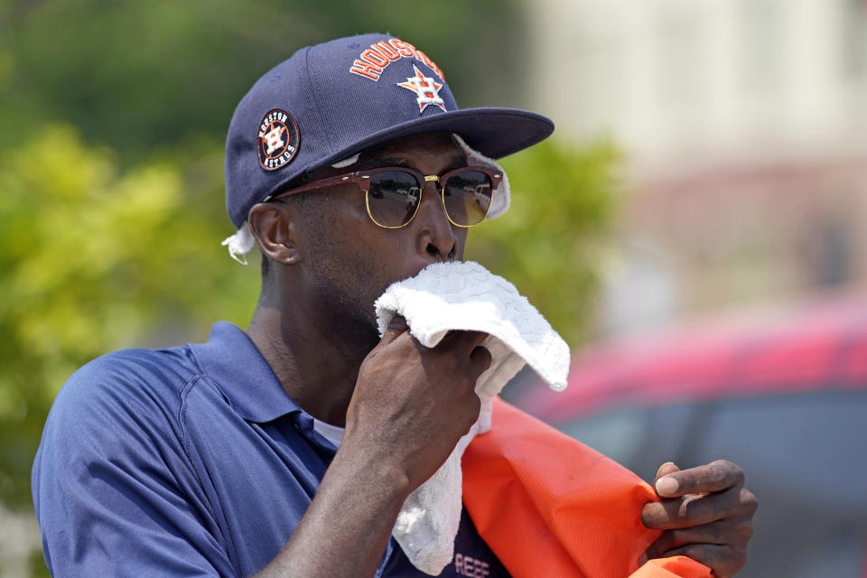 Parking lot attendant Donnay Wright wipes the sweat from his face while working in the heat outside Minute Maid Park before a baseball game between the Cincinnati Reds and Houston Astros Saturday, June 17, 2023, in Houston. (AP Photo/David J. Phillip)