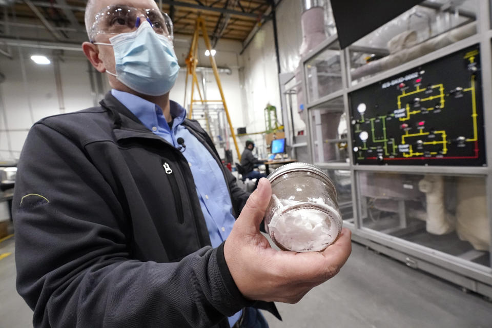 TerraPower's Michael Anderson, manager of test engineers and technicians, holds a glass jar holding purified salt during a tour of the nuclear reactor development facility, Thursday, Jan. 13, 2022, in Everett, Wash. TerraPower plans to make its plant useful for today's energy grid with ever more renewable power. A salt heat "battery" will allow a nuclear plant to ramp up electricity production on demand, offsetting dips in electricity when the wind isn't blowing and sun isn't shining. (AP Photo/Elaine Thompson)