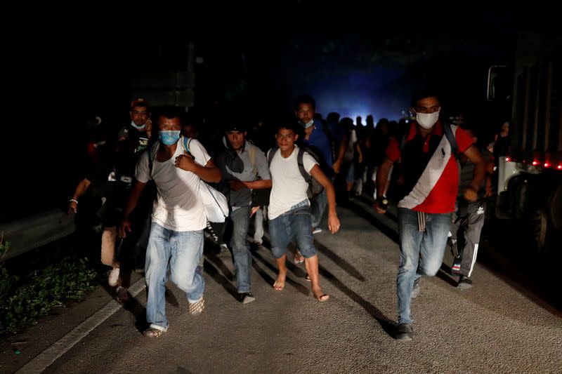 Honduran migrants trying to reach the U.S. run away after hurling stones to Guatemalan soldiers blocking a road to stop migrants from reach the Mexico's border, in San Pedro Cadenas