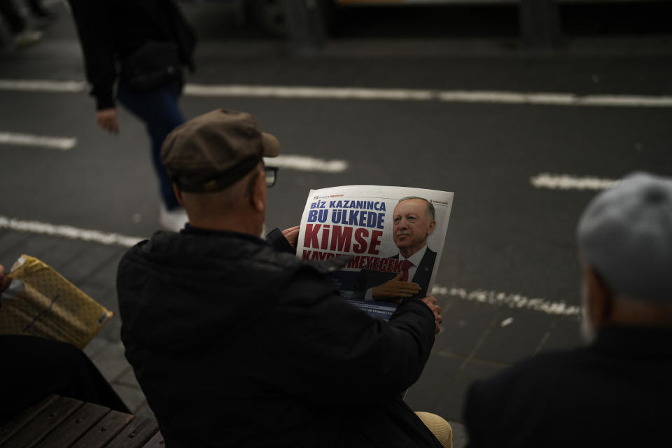 A man reads an election handout of Turkish President and People's Alliance's presidential candidate Recep Tayyip Erdogan in Istanbul, Turkey, Tuesday, May 23, 2023. Two opposing visions for Turkey’s future are on the ballot when voters return to the polls Sunday for a runoff presidential election, which will decide between an increasingly authoritarian incumbent President Recep Tayyip Erdogan and challenger Kemal Kilicdaroglu, who has pledged to restore democracy. (AP Photo/Francisco Seco)