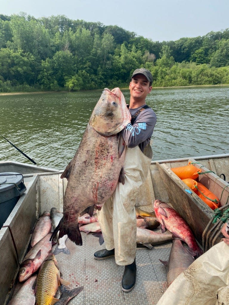 Andrew Wieland, large river fisheries ecologist with the Illinois Natural History Survey, holds a 109-pound bighead carp caught last week by commercial fisherman Charlie Gilpin Jr. in an Illinois River backwater.