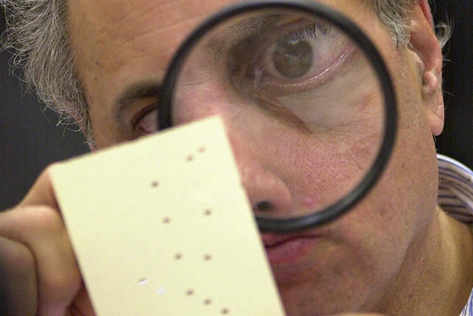 FILE - This Nov. 24, 2000 file photo shows Broward County canvassing board member Judge Robert Rosenberg using a magnifying glass to examine a disputed ballot at the Broward County Courthouse in Fort Lauderdale, Fla. Twenty years ago, in a different time and under far different circumstances than today, it took five weeks of Florida recounts and court battles before Republican George W. Bush prevailed over Democrat Al Gore by 537 votes. (AP Photo/Alan Diaz, File)