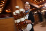 A waitress carries eleven beer mugs at a beer tent.