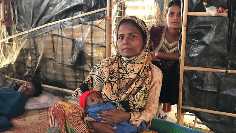 A refugee mom of eight holds her newborn in her tarp and bamboo home in January 2018.