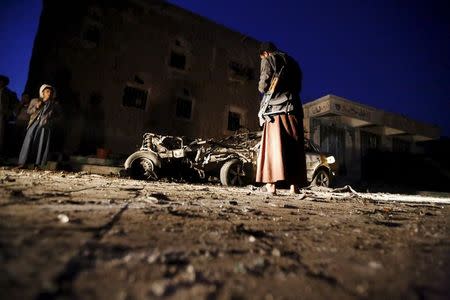 An armed man looks at the wreckage of a car at the site of a car bomb attack in Yemen's catpital Sanaa June 17, 2015. REUTERS/Khaled Abdullah