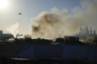 A Russian Emergency Situations Ministry helicopter dumps water on fire at a warehouse in Moscow, Russia, Saturday, June 19, 2021. A large fire broke out at a fireworks depot in the center of Moscow. The fire is raging at the area of 500 square meters, Russia emergency services said in the statement. (AP Photo/Pavel Golovkin)