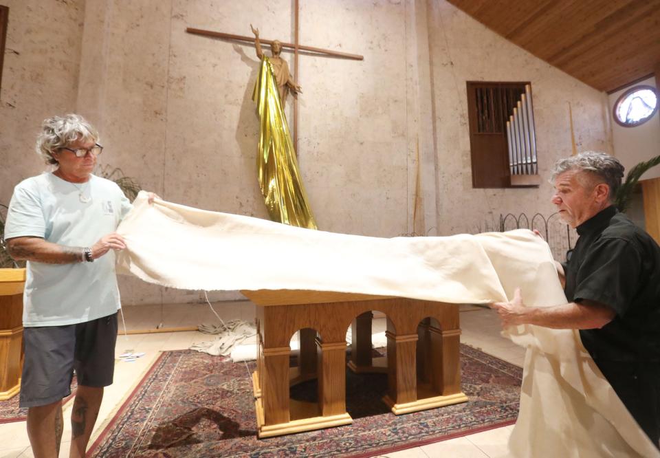 With help from a church member, Father Phil Egitto decorates for Easter at Our Lady of Lourdes Catholic Church in Daytona Beach. The church again will be presenting two Easter services at the Daytona Beach Bandshell, a task that requires work from a cast of roughly 50 church members.