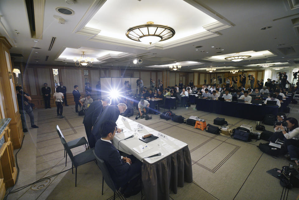 Tetsuo Yukioka, managing director of Tokyo Medical University, right standing at table, and Keisuke Tomizawa, a representative of the head of Tokyo Medical University, left standing, bow during a press conference Tuesday, Aug. 7, 2018, in Tokyo. The school has been investigating a reported allegation that it has discriminated against female applicants. (AP Photo/Eugene Hoshiko)