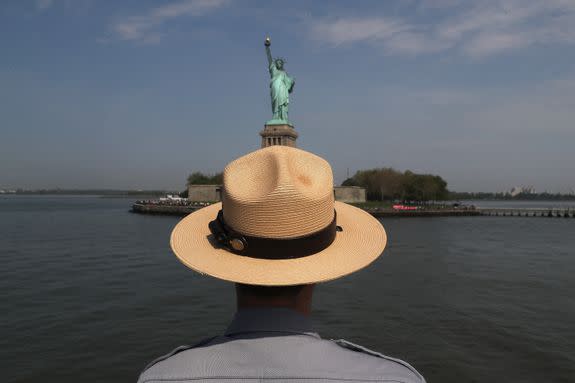 A park ranger standing in front of the Statue of Liberty.