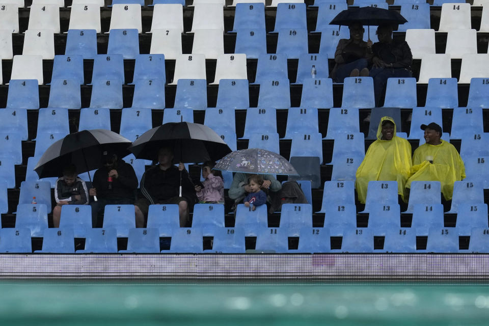 Fans wait as rain delayed the start for the first T20 cricket match between South Africa and West Indies, at Centurion Park, South Africa, in Pretoria, South Africa, Saturday, March 25, 2023. (AP Photo/Themba Hadebe)