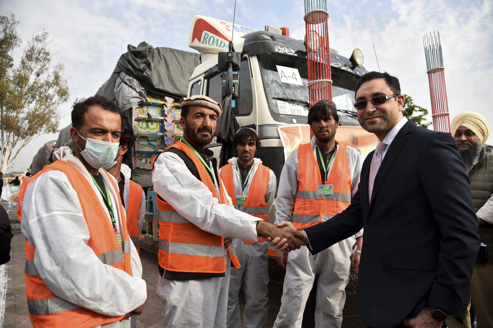 Afghanistan’s ambassador to India Farid Mamundzay, right, shakes hands with an Afghan driver before the trucks carrying wheat from India passed through the Attari-Wagah border between India and Pakistan, near Amritsar, India, Tuesday, Feb. 22, 2022. India's foreign ministry says it has sent off tons of wheat to Afghanistan to help relieve desperate food shortages, after New Delhi struck a deal with neighboring rival Pakistan to allow the shipments across the shared border. (AP Photo/Prabhjot Gill)