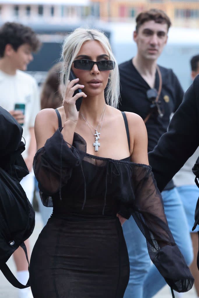 <p>Kim wears a chic, piecey updo with layered chain pendants, minimal sunglasses and a stretchy mini dress with bardot top. </p>