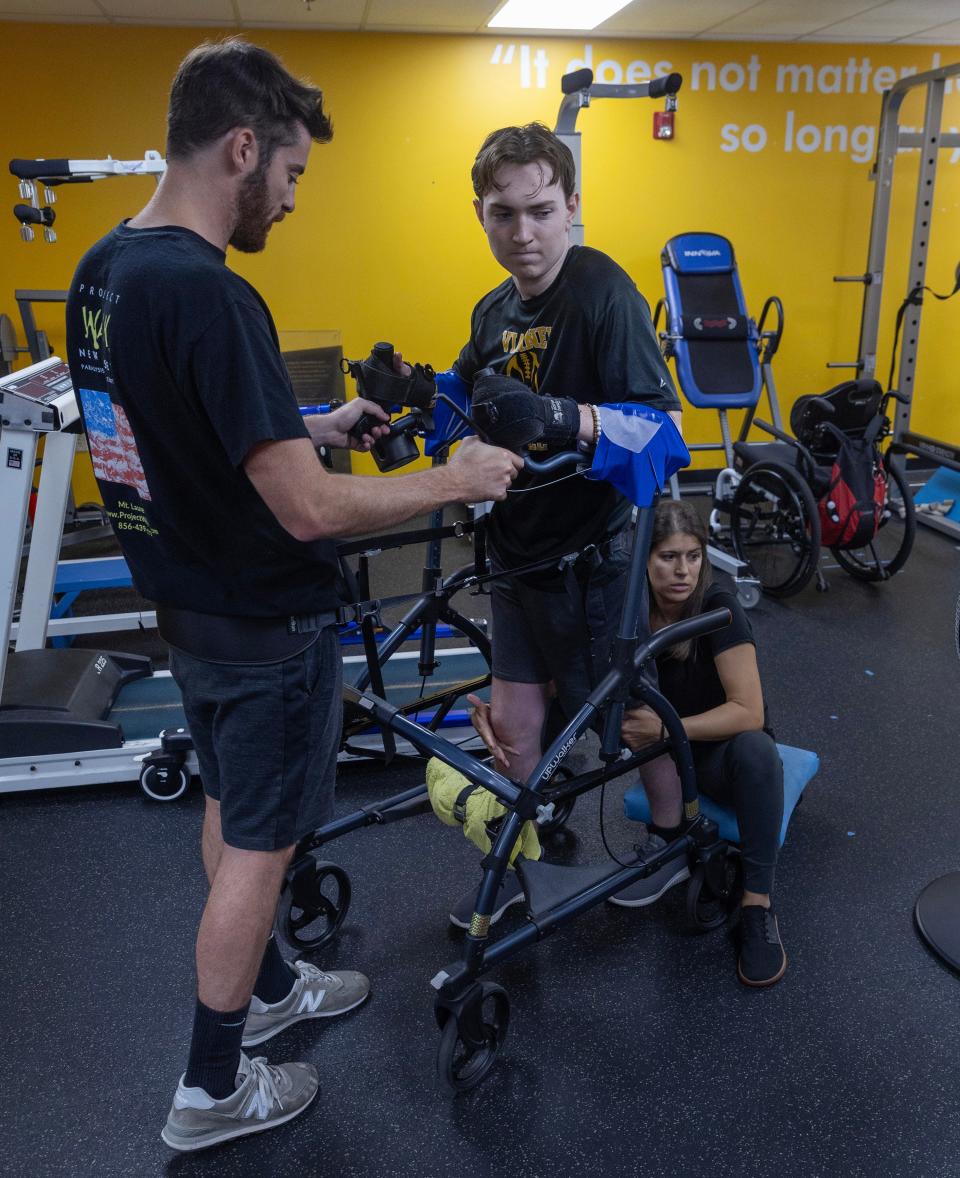 Matt Fumo and Daniella Rivka help Aaron Van Trease as he works with the wheeled walker, slowly going around the facility at Project Walk in Mount Laurel.