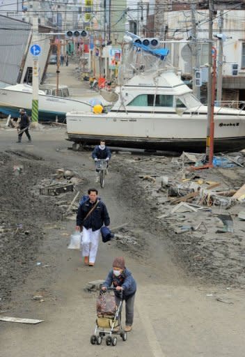 Photo dated March 15 shows Japanese citizens walking past a boat that was catapulted by the deadly tsunami in the city of Ishinomaki in Miyagi prefecture. A year after whole neighbourhoods full of people were killed by the Japanese tsunami, rumours of ghosts swirl in Ishinomaki as the city struggles to come to terms with the awful tragedy