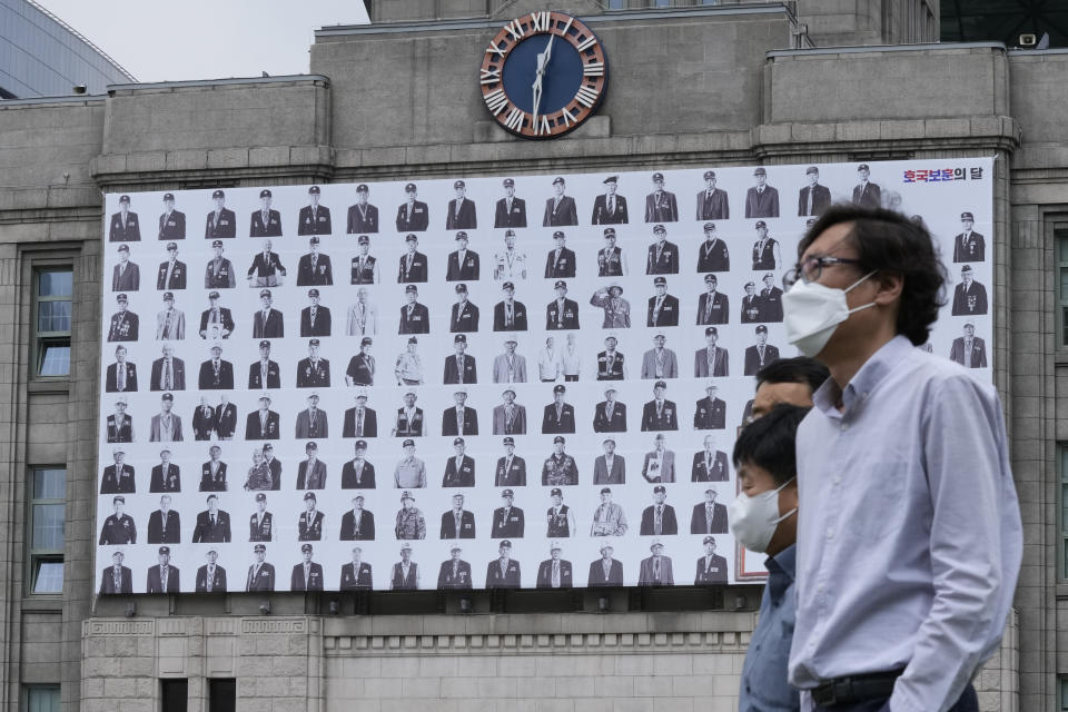 FILE - People pass by a banner showing portraits of Korean War veterans on the eve of the 71st anniversary of the outbreak of the Korean War in front of Seoul City Hall in Seoul, South Korea, on June 24, 2021. (AP Photo/Ahn Young-joon, File)