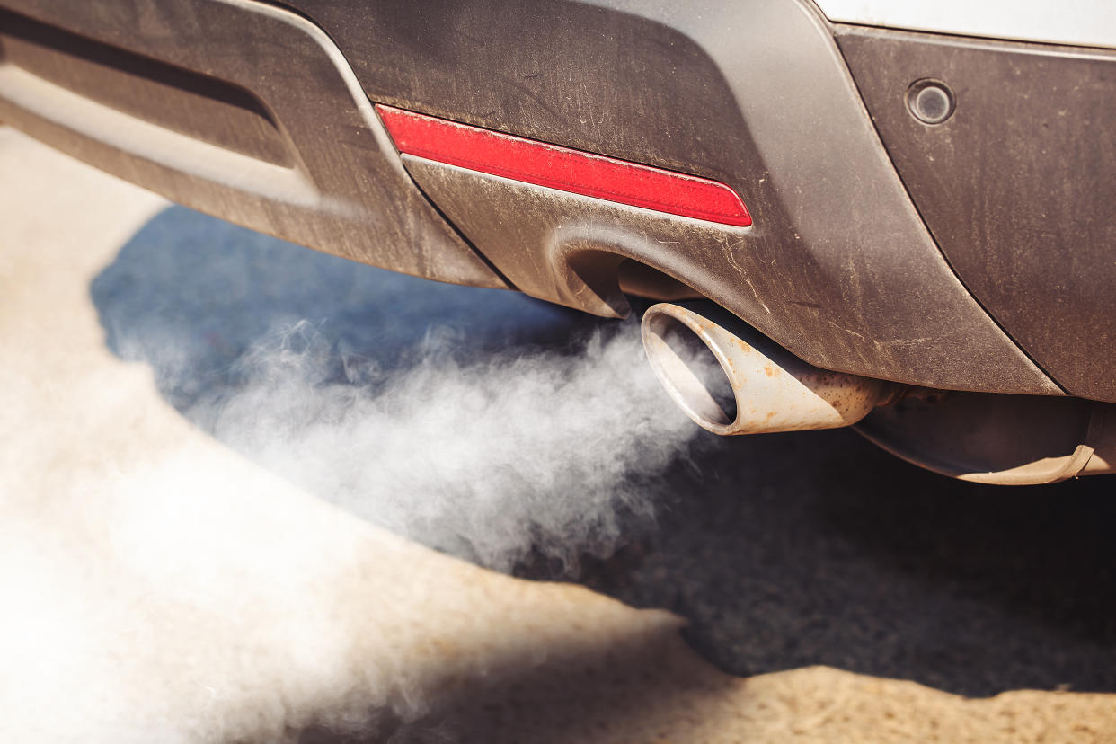 air pollution from dirty and aged vehicle exhaust pipe on road