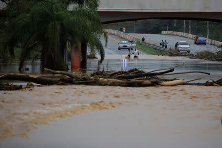 People wade through a flooded expressway after the area was hit by Hurricane Maria in Yauco, Puerto Rico September 21, 2017. REUTERS/Carlos Garcia Rawlins