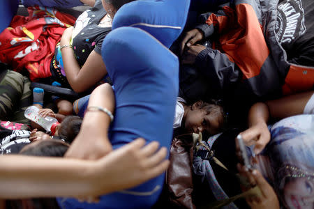 Linda looks up between her brother and mother while riding on a bus with fellow Central American migrants, as part of a caravan moving through Mexico toward the U.S. border, on a highway in Puebla state, Mexico April 6, 2018. REUTERS/Edgard Garrido