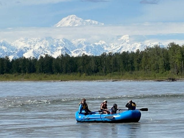 With Denali in the background, adventurers on a raft in the Talkeetna River enjoy the sunshine in Alaska.