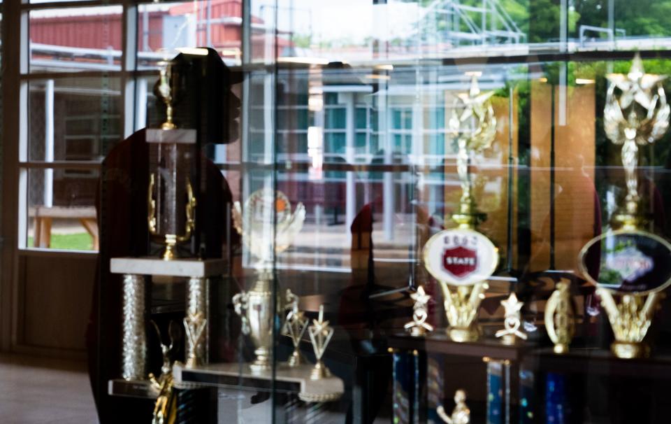 Johnston High School Class of 1973 graduate Rodrick Brown is reflected in the trophy case containing awards earned by Johnston High School. Though the school building in East Austin is now home to LASA, mementos from Johnston have been kept.