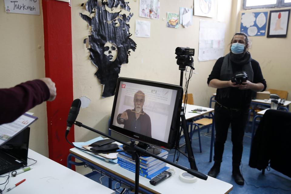 Music teacher, Nikos Karadosidis, right, listens to prison school director Petros Damianos before recording lessons at a classroom of Avlona's prison school, north of Athens, Wednesday, Feb. 10, 2021. With Greece's schools shut due to the pandemic, all lessons have gone online. But the online world isn't within reach of everyone _ and particularly not within reach of the students of Avlona Special Youth Detention Center, where internet devices are banned by law from the cells. (AP Photo/Thanassis Stavrakis)