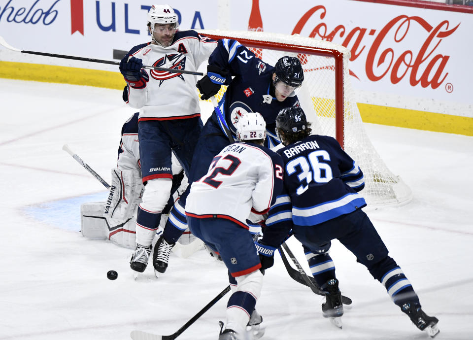 Columbus Blue Jackets' Erik Gudbranson (44) and Winnipeg Jets' Dominic Toninato (21) work for position in front of the Blue Jackets' net as a shot comes in during the second period of an NHL hockey game Tuesday, Jan. 9, 2024, in Winnipeg, Manitoba. (Fred Greenslade/The Canadian Press via AP)