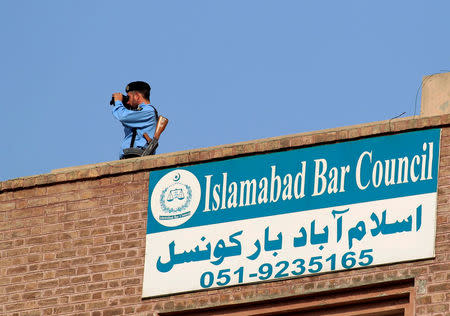 A policeman looks through binoculars from the rooftop of the National Accountability Bureau (NAB) court in Islamabad, Pakistan October 19, 2017. REUTERS/Faisal Mahmood